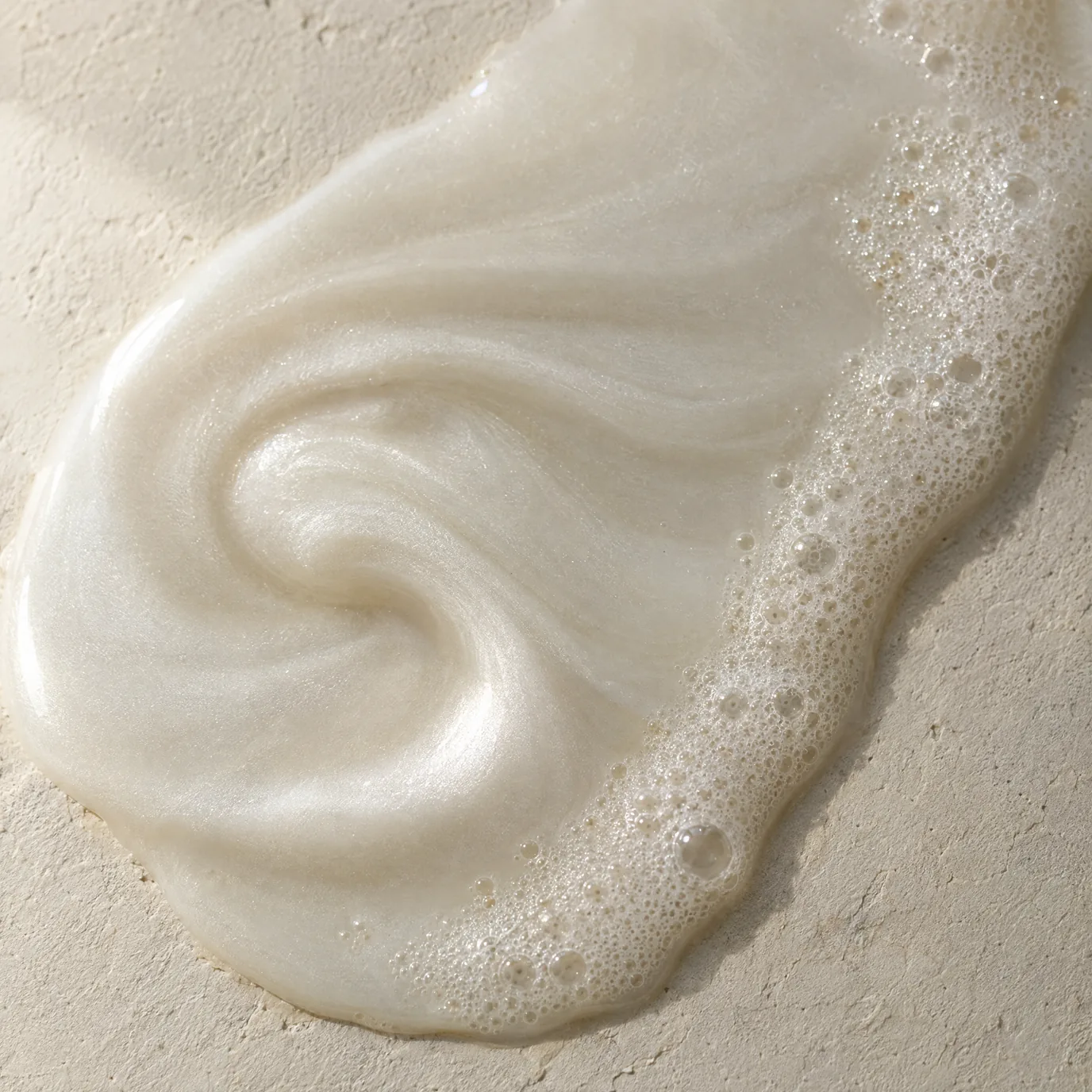 A pearlescent white liquid with fine foam along one edge.